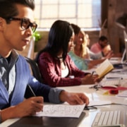 Line of people working on several computers at desk