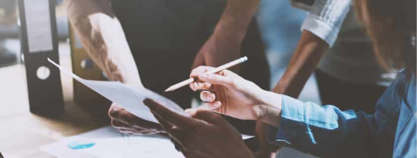 Hand pointing at paper with pencil