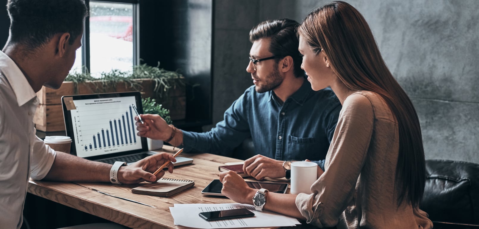 Three coworkers looking at graphs on laptop