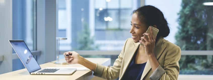 Woman on cellphone while working on laptop