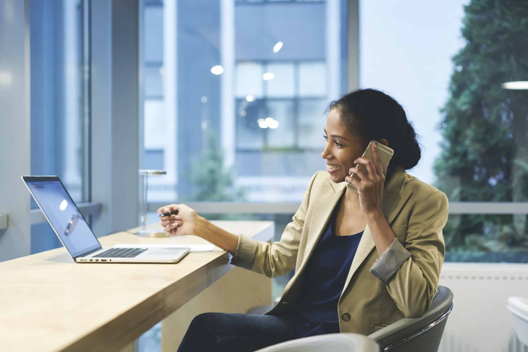 Woman on cellphone while working on laptop