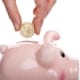 Hand dropping coin in piggy bank