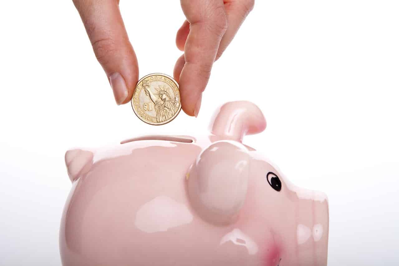 Hand dropping coin in piggy bank