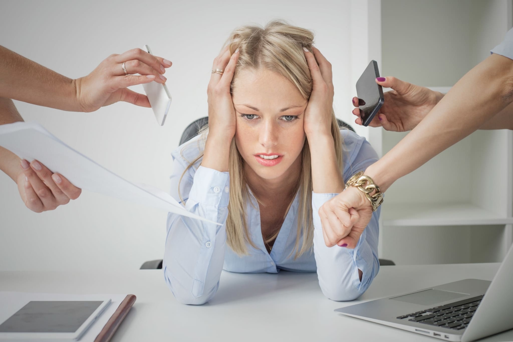 Business woman stressed with numerous people handing her papers and phones