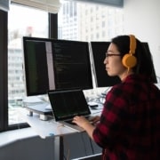overcoming alert fatigue - employee in front of three computer screens looks out the window