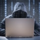 hacker in hoodie types on computer with code in background - security incident response panel