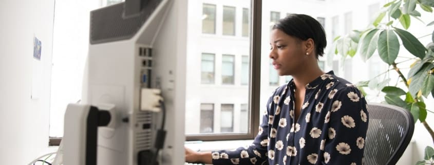 woman works at office computer to increase productivity and security through web filtering