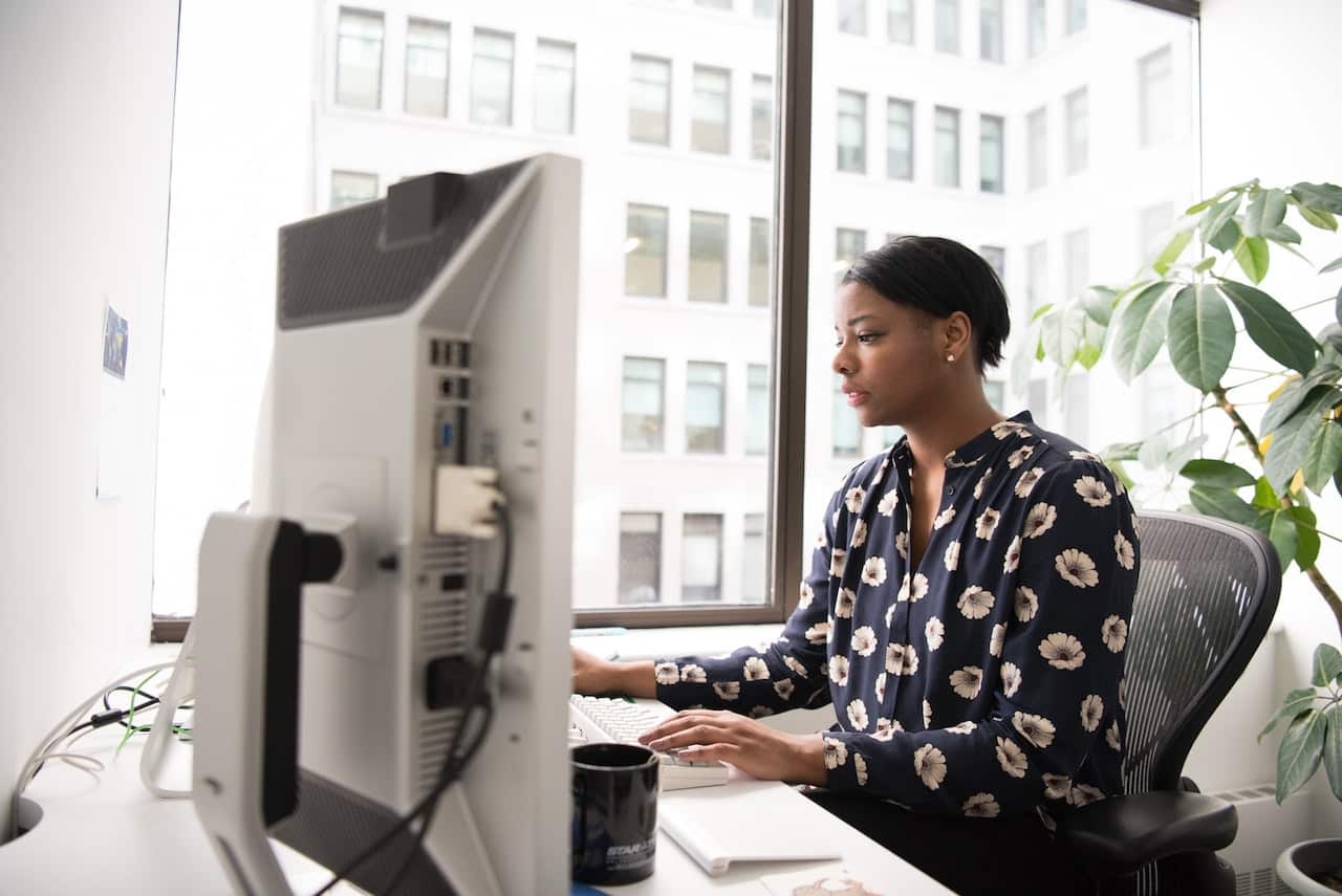 woman works at office computer to increase productivity and security through web filtering