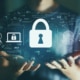 lock icon and other computer symbols above hands representing cybersecurity