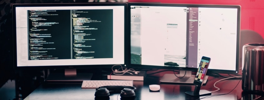 two computer screens set up as part of the business hardware at an Oklahoma IT company